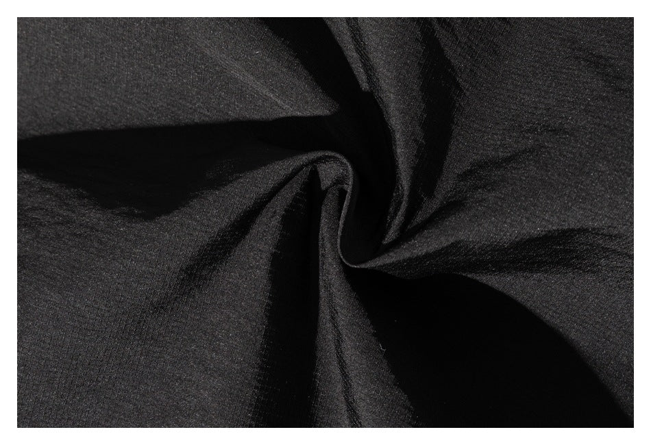 Close-up of black garment fabric gathered into folds, showing its fine surface texture.