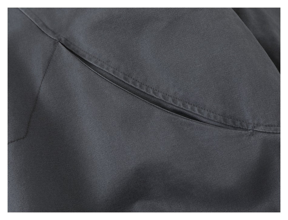 Close-up of a curved seam and panel construction on the charcoal jacket.