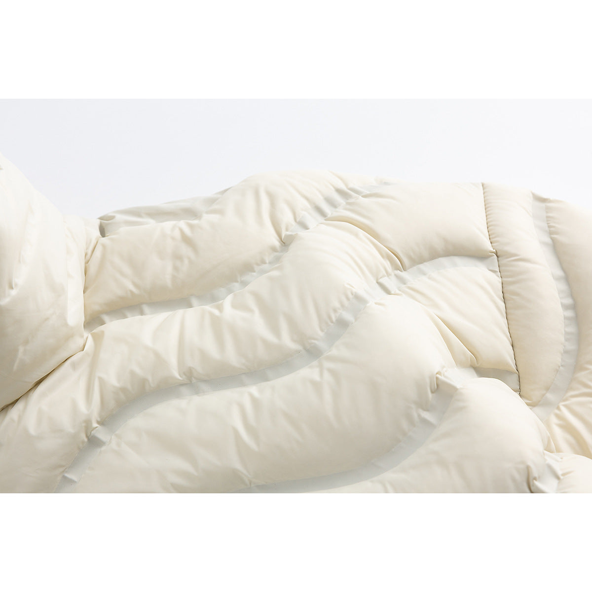 Close-up of the ivory jacket's padded wavy quilting and panel seams.