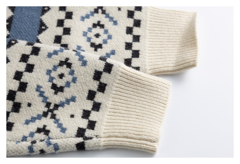 Close-up of two ivory rib-knit sleeve cuffs beside the sweater's black and dusty blue geometric pattern.