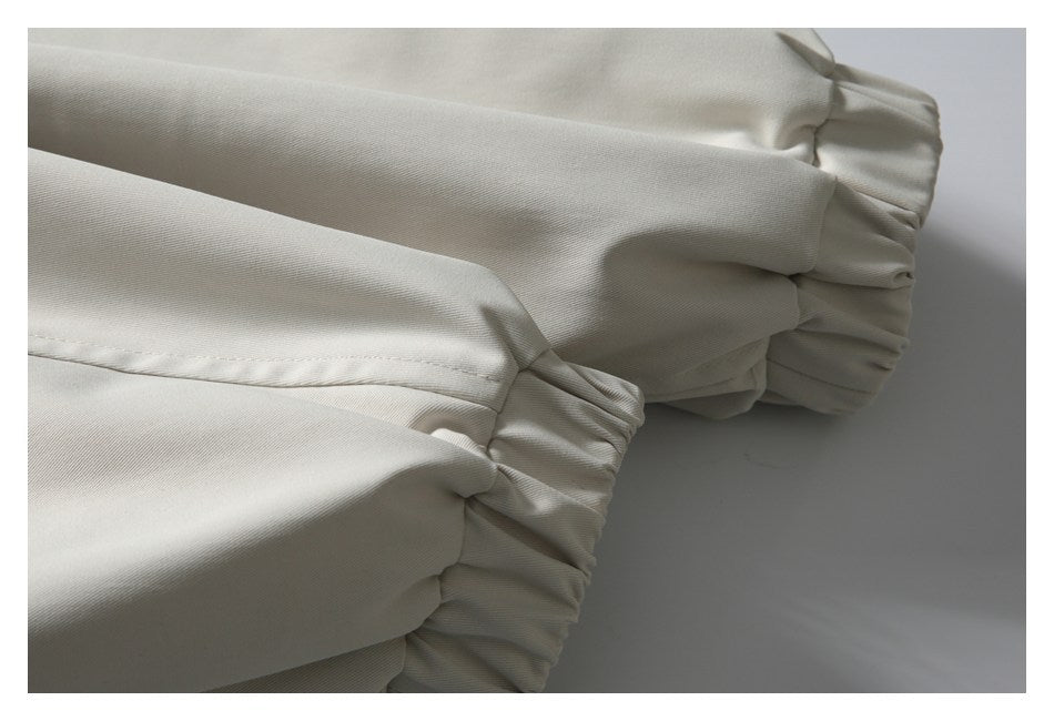Close-up of an off-white garment's gathered elastic edge and seam stitching.