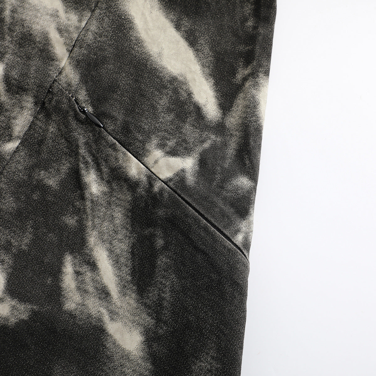 Close-up of a diagonal zip pocket on a black and cream abstract-patterned shirt.