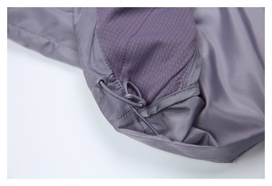 Close-up of a gray-purple jacket hem with a looped drawcord adjuster beside a mesh panel.