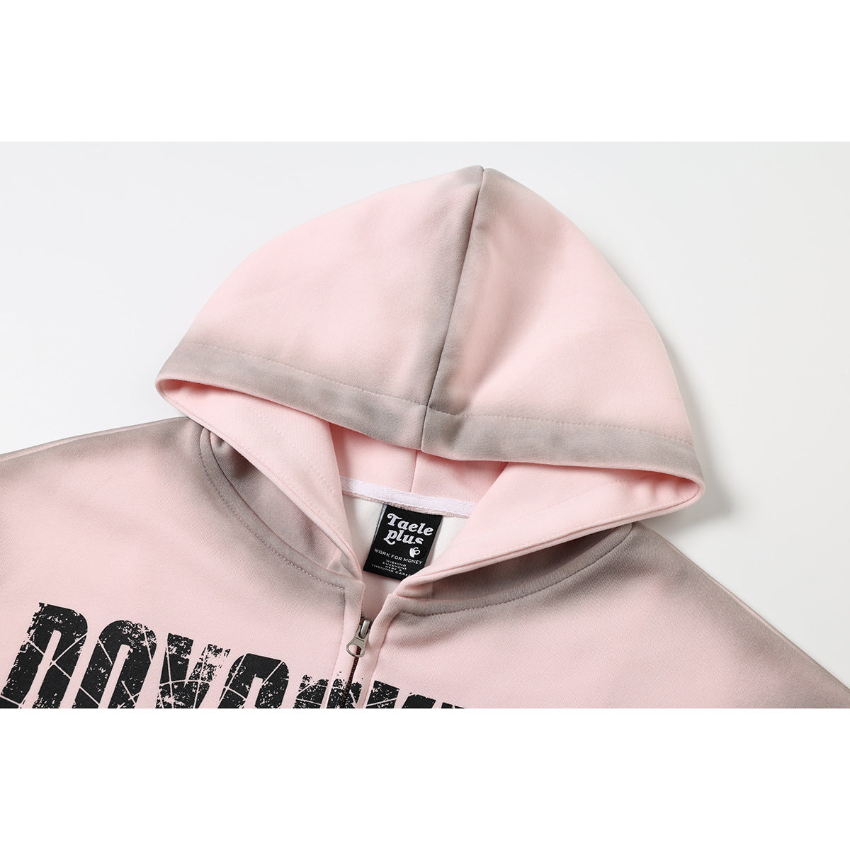 Close-up of a pale pink zip hoodie showing its hood, neck label, zipper, and part of a distressed black chest print.