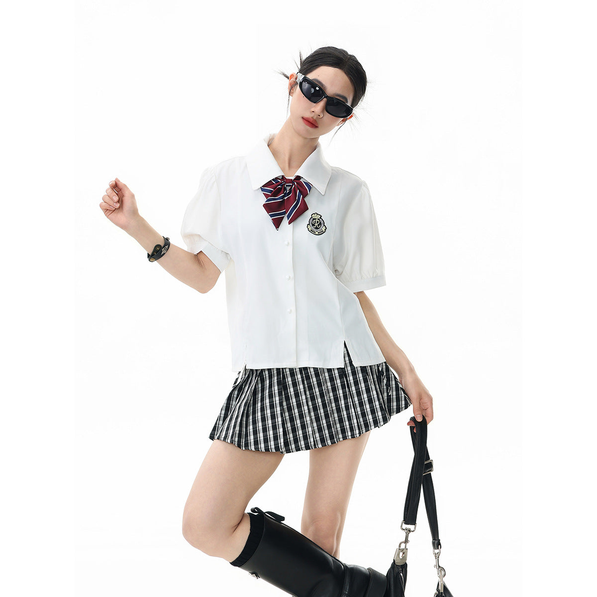 Model wearing a white collared shirt with a striped bow and black-and-white plaid skirt, shown in a closer pose.