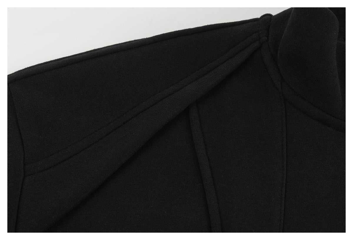 Close-up of the black jacket's shoulder, showing layered seams and a gathered pleat.