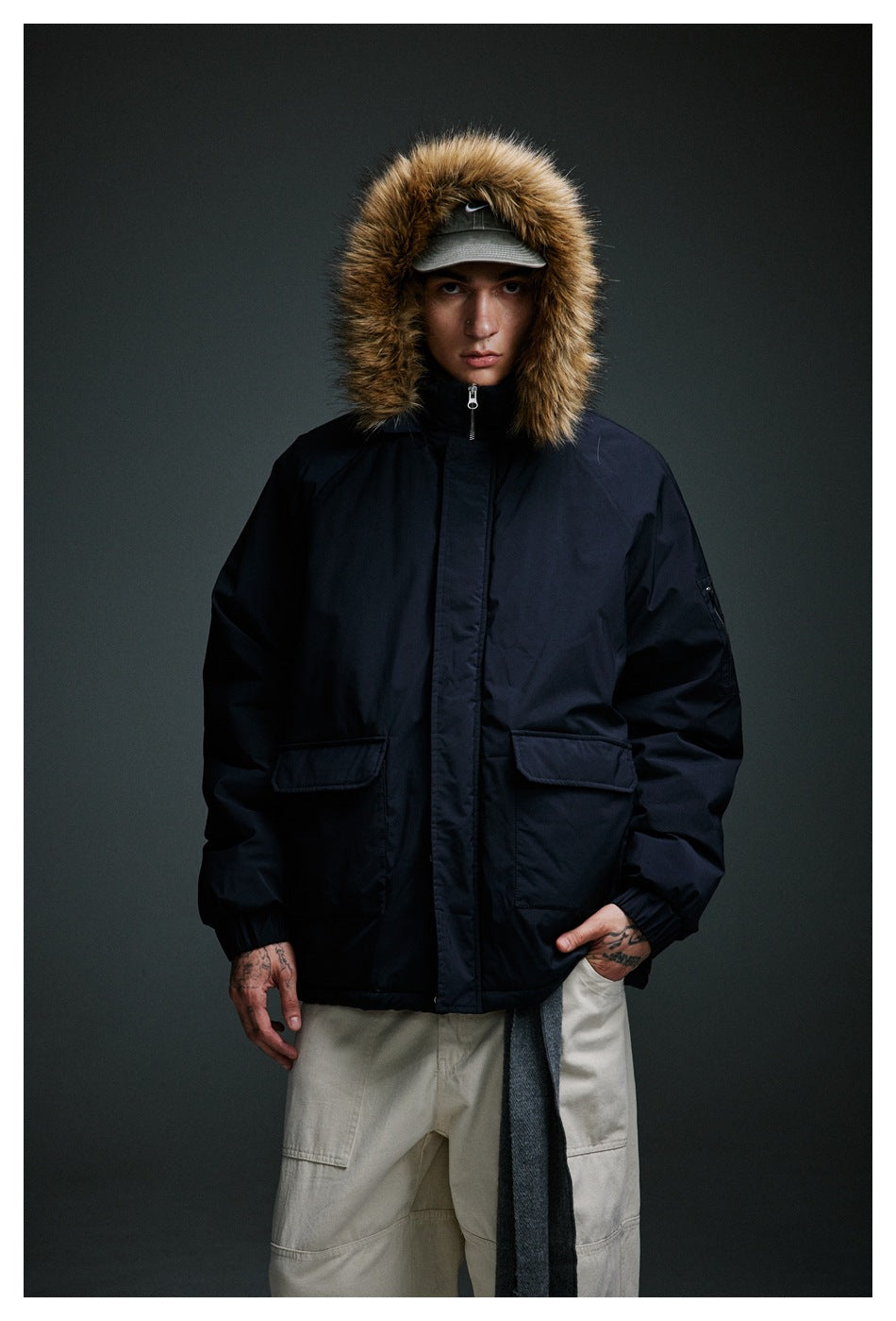 Front view of a model wearing a dark navy fur-trim hooded jacket with flap pockets and a covered closure.