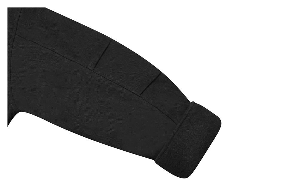 Close-up of a black garment sleeve showing panel seams and a wide folded cuff.