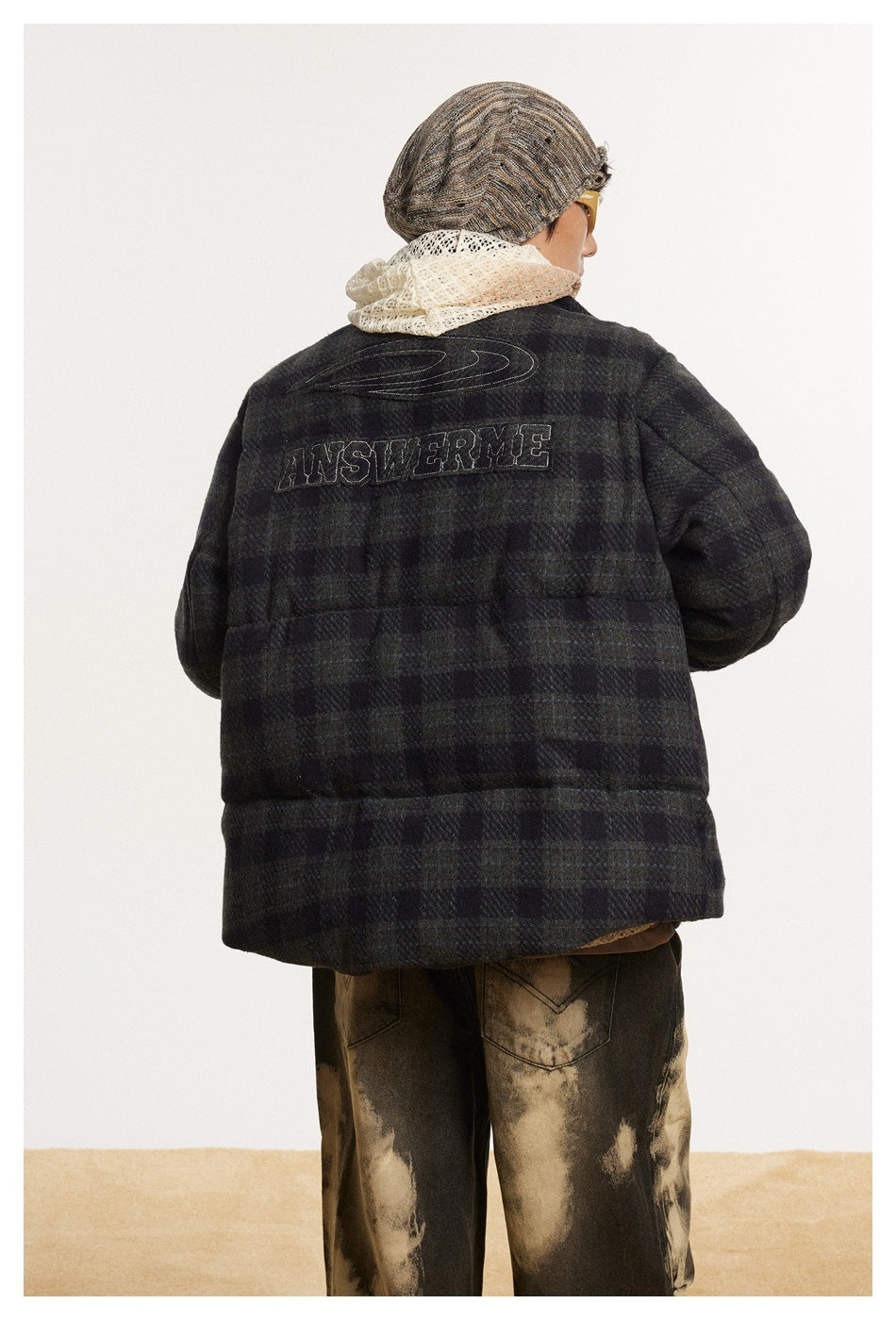 Back view of a model wearing a dark charcoal plaid jacket with outlined lettering across the upper back.
