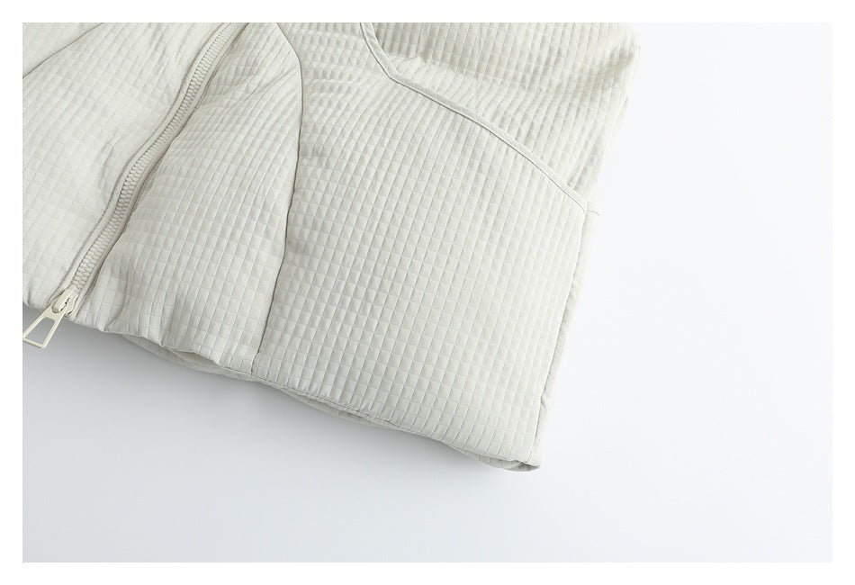 Close-up of the ivory quilted garment's lower front, zipper, and hem.