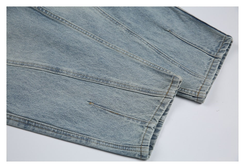 Close-up of two overlapping light-wash denim jean hems with contrast stitching.