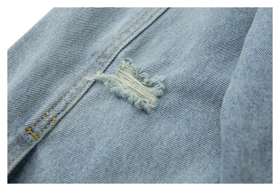 Close-up of a frayed distressed patch on light blue denim beside a double-stitched seam.