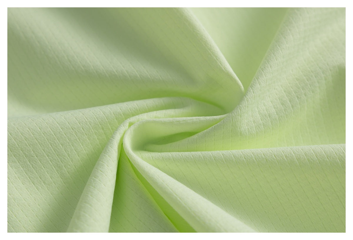 Close-up of pale lime fabric draped into soft folds, showing its subtle surface texture.