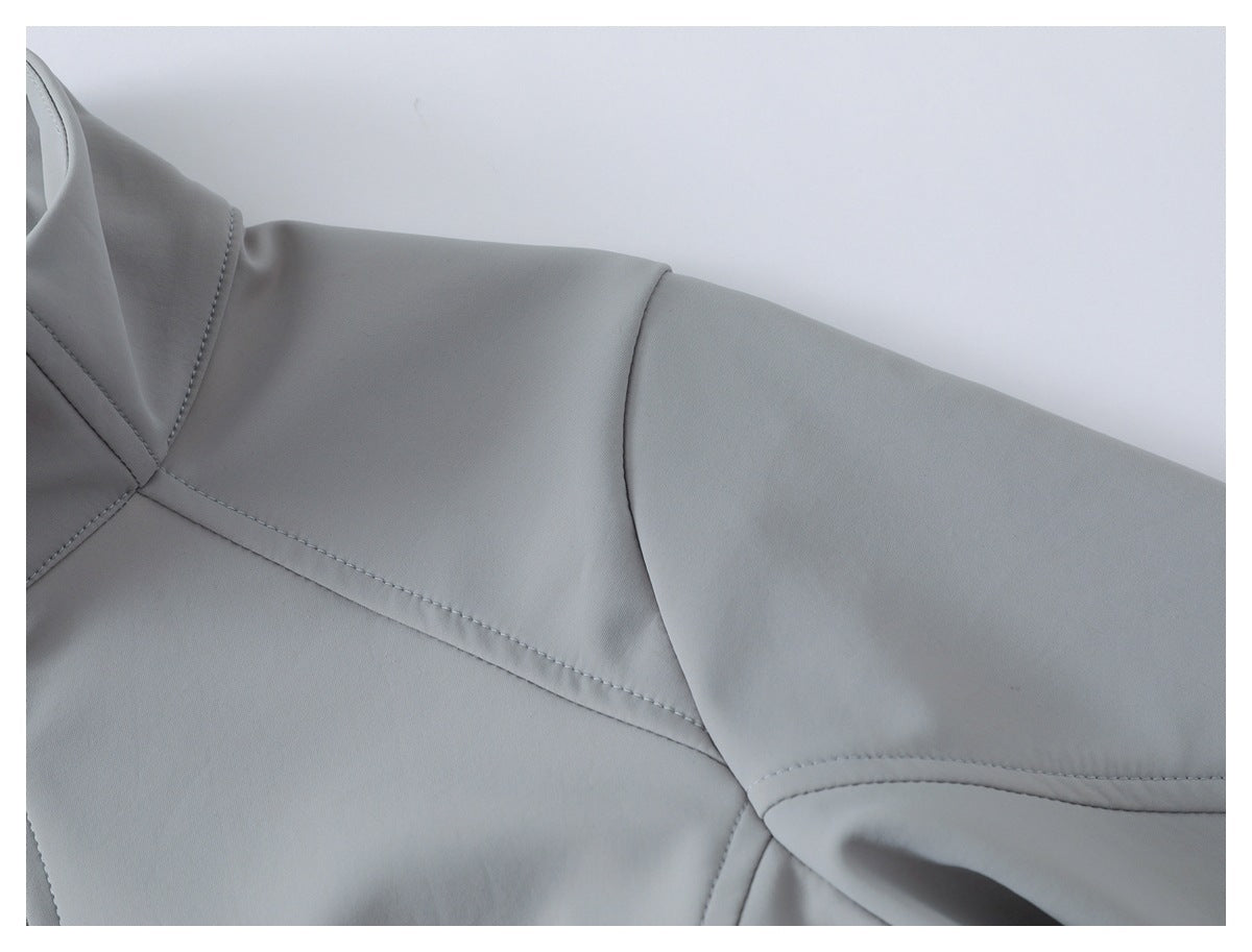 Close-up of a light gray jacket's shoulder and sleeve, showing curved panel seams and stitching.