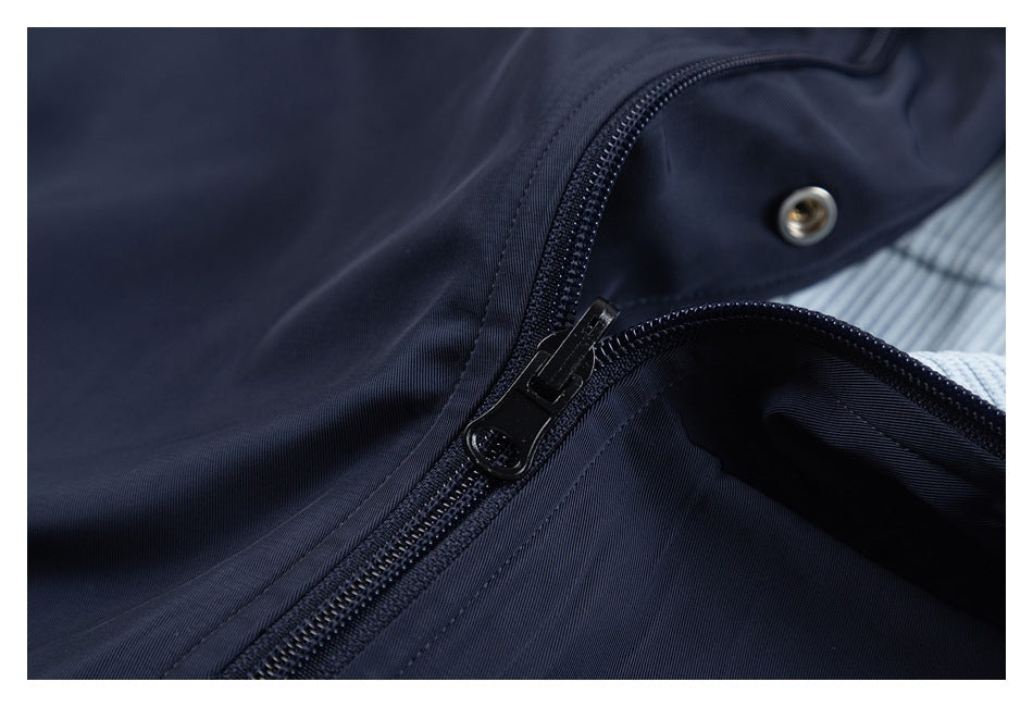 Close-up of a dark navy zipper and metal snap fastening with pale blue ribbed fabric underneath.
