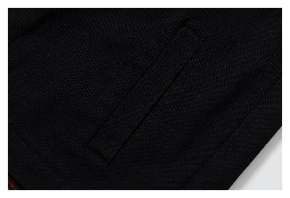 Close-up of a narrow stitched pocket on black fabric.