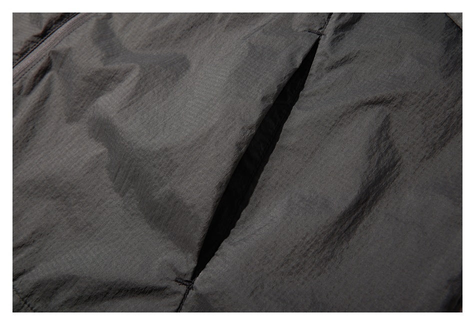 Close-up of dark charcoal garment fabric with a diagonal seam and narrow black opening.