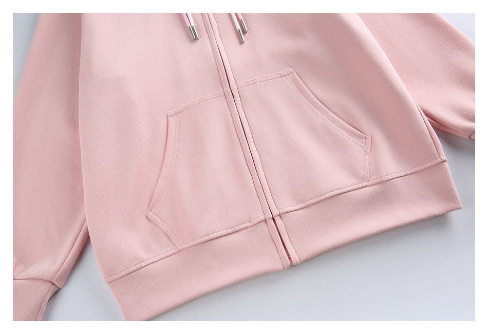 Close-up of the pale pink hoodie’s front kangaroo pocket, center zipper and ribbed hem.