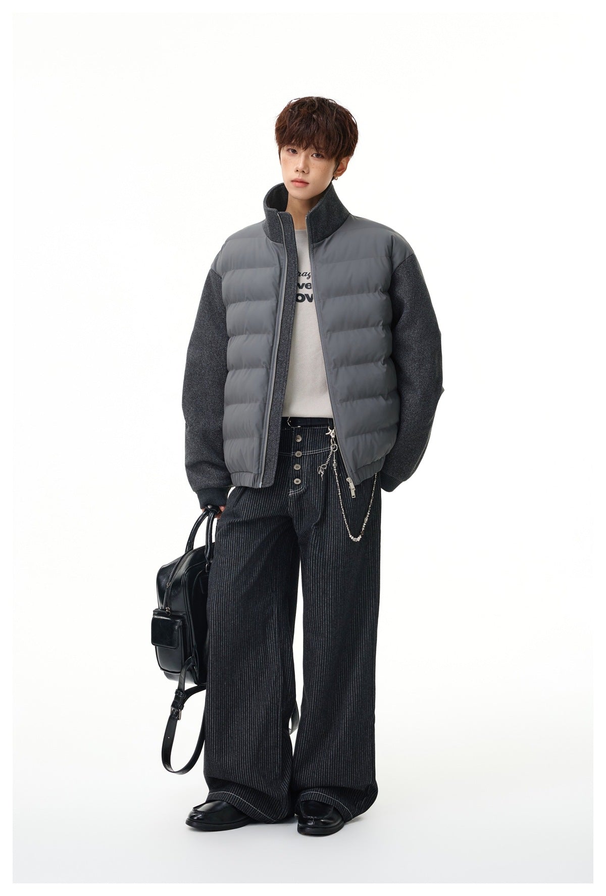 Full-length view of a model wearing a charcoal gray quilted-front jacket with textured sleeves and a high collar.