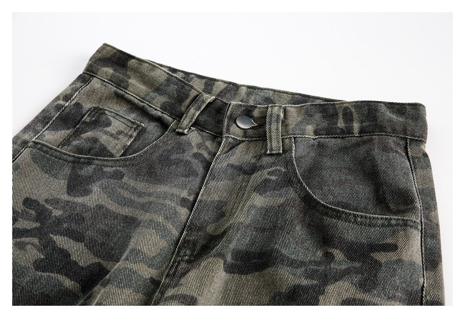 Close-up of the front waistband, button, belt loops, and curved pockets on dark camouflage pants.