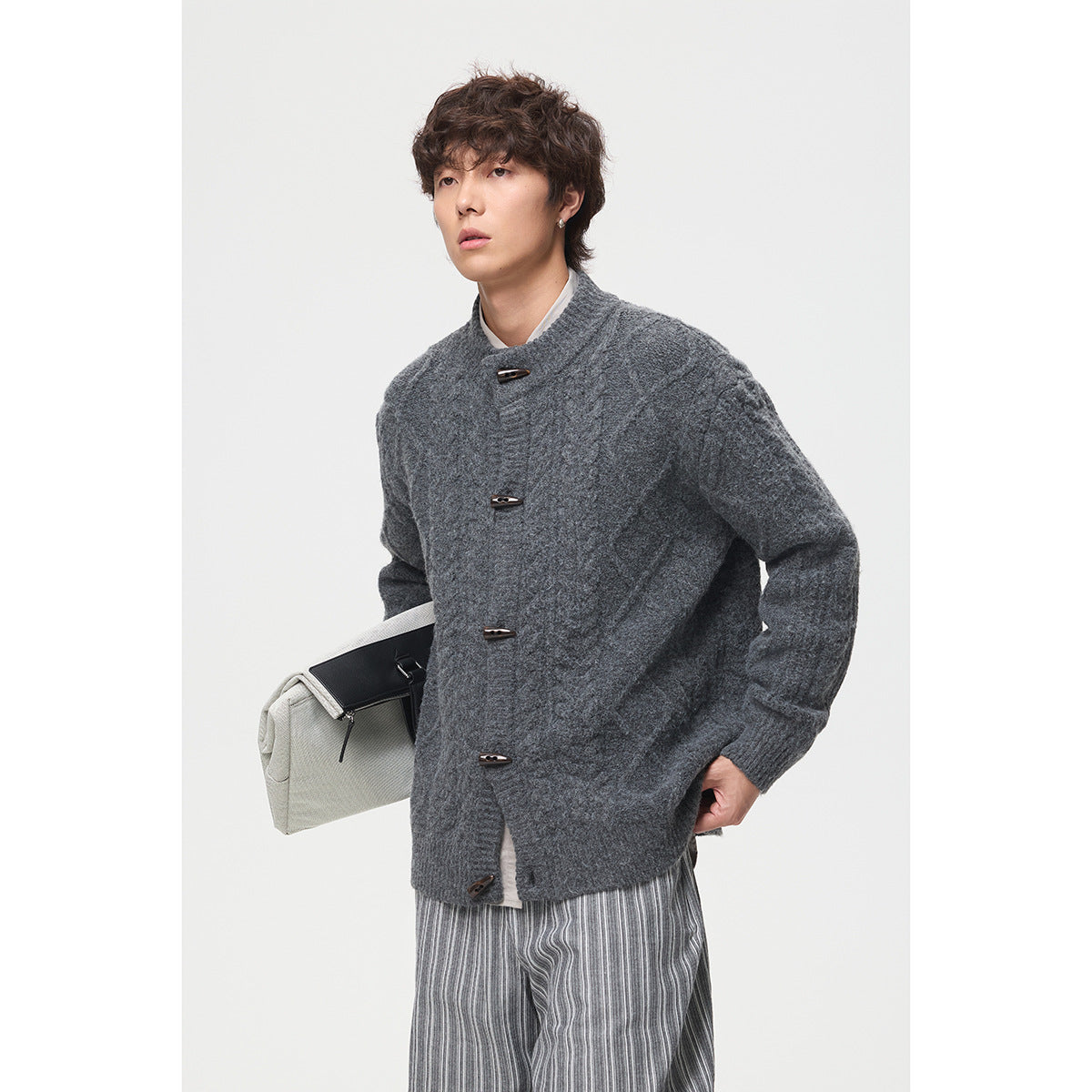 Model wearing a charcoal cable-knit cardigan with a stand collar and toggle buttons, shown from the front.