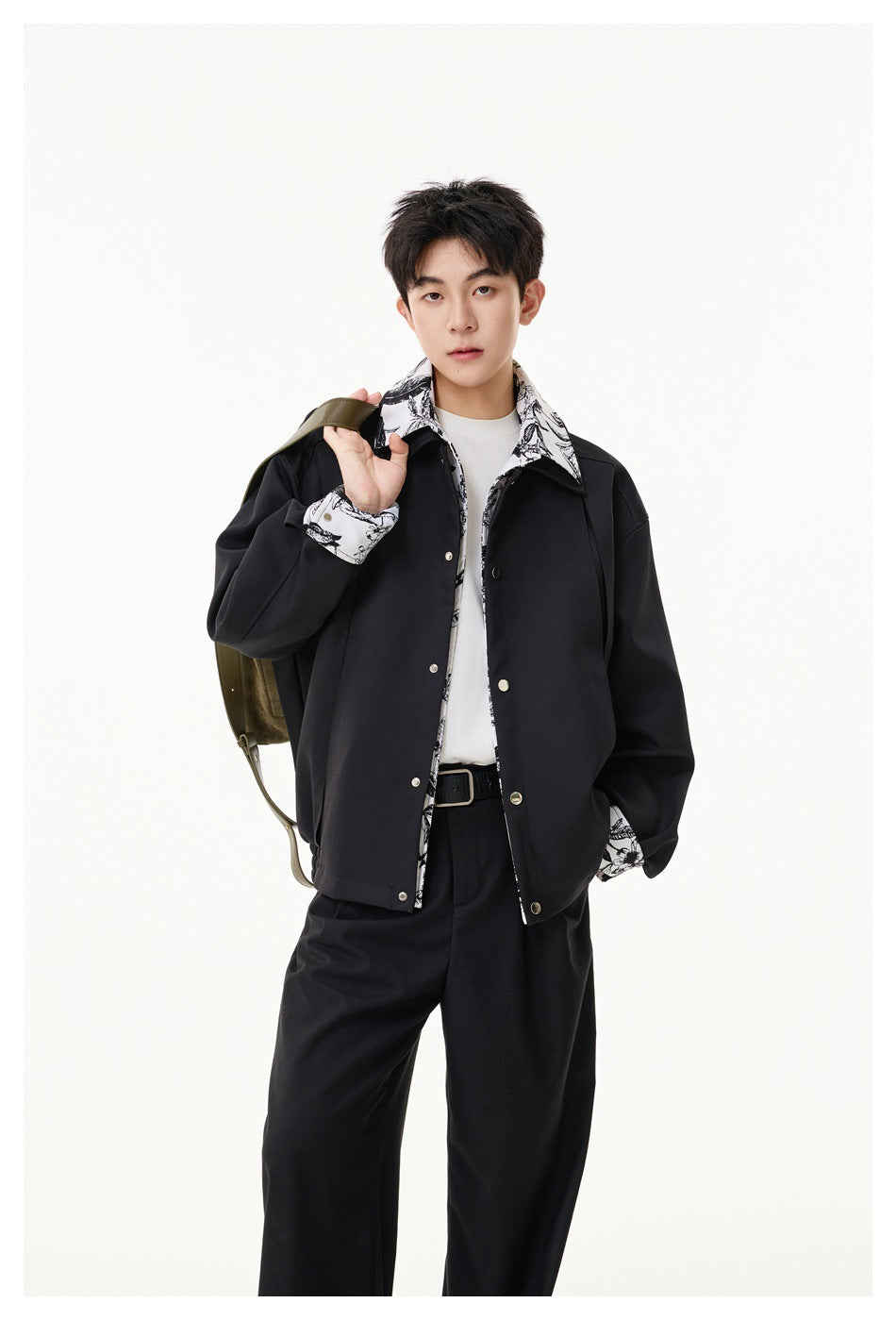 Model wearing a black jacket with a black-and-white floral-print collar, cuffs and trim, paired with black trousers.