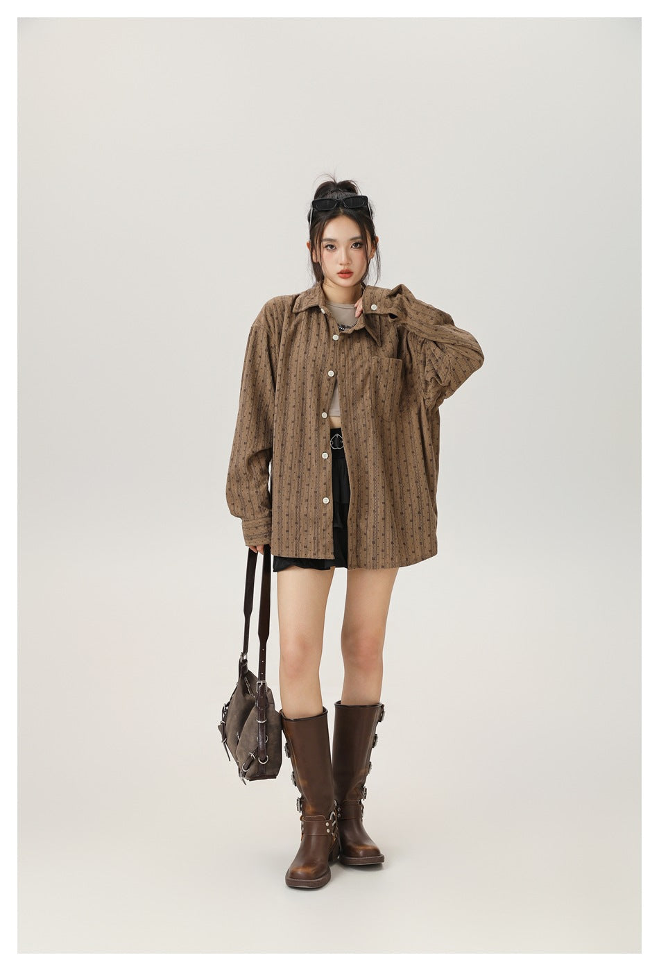 Model wearing the coffee brown striped shirt open over a cropped top, black skirt and brown boots