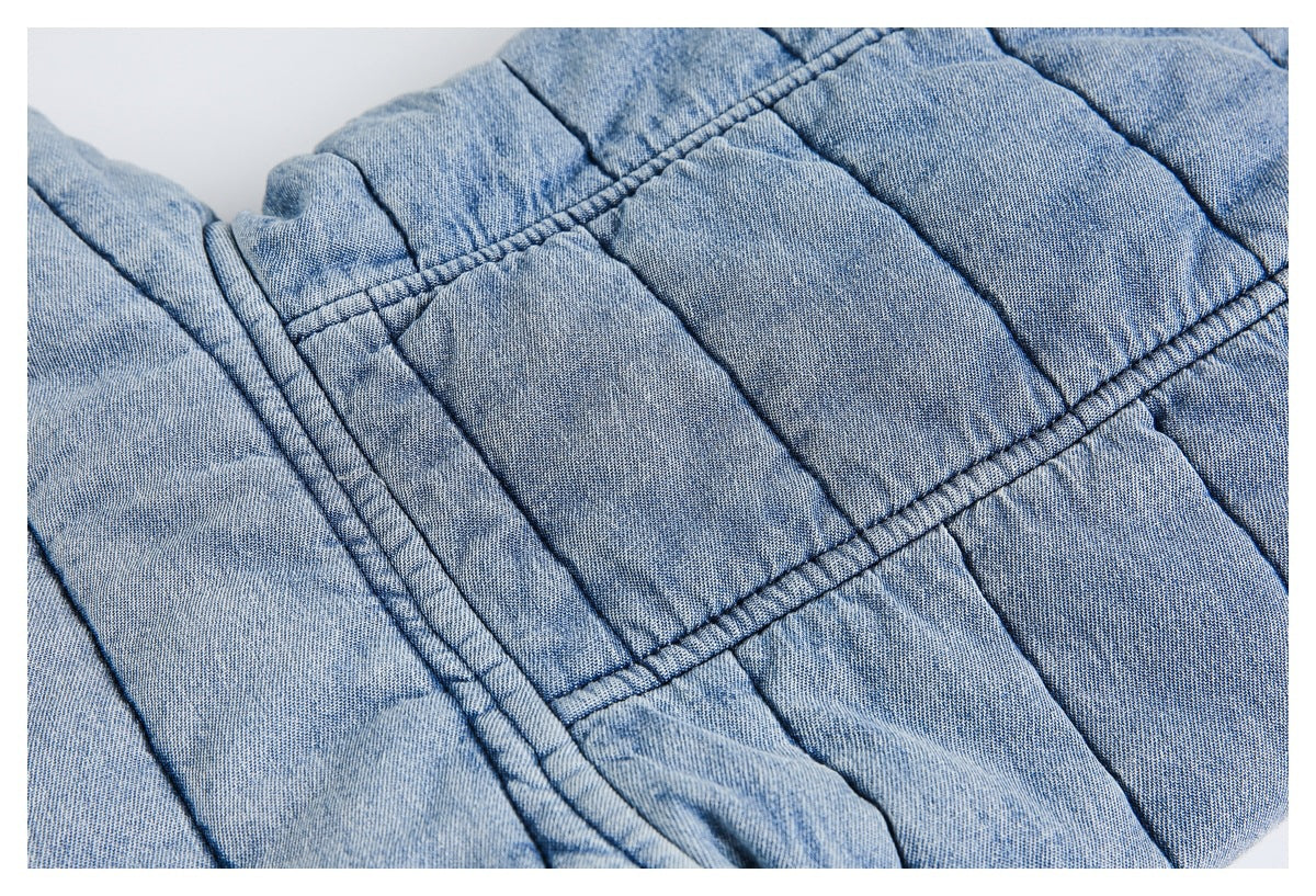 Close-up of quilted light blue jacket fabric and intersecting stitched seams.