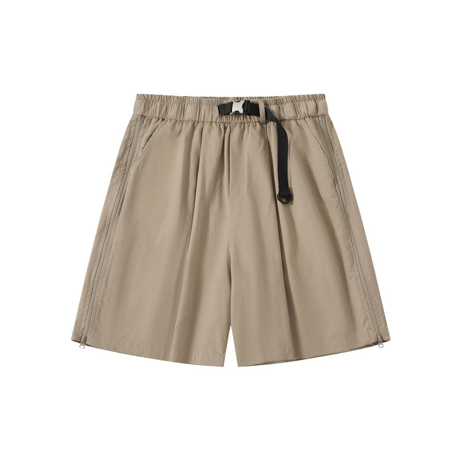 Front view of tan loose shorts with an elastic waistband, black buckle belt, angled pockets, and side zippers.