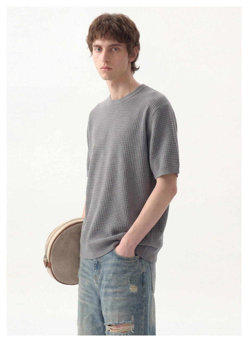 Three-quarter view of a model wearing a gray textured short-sleeve crewneck top and distressed jeans.