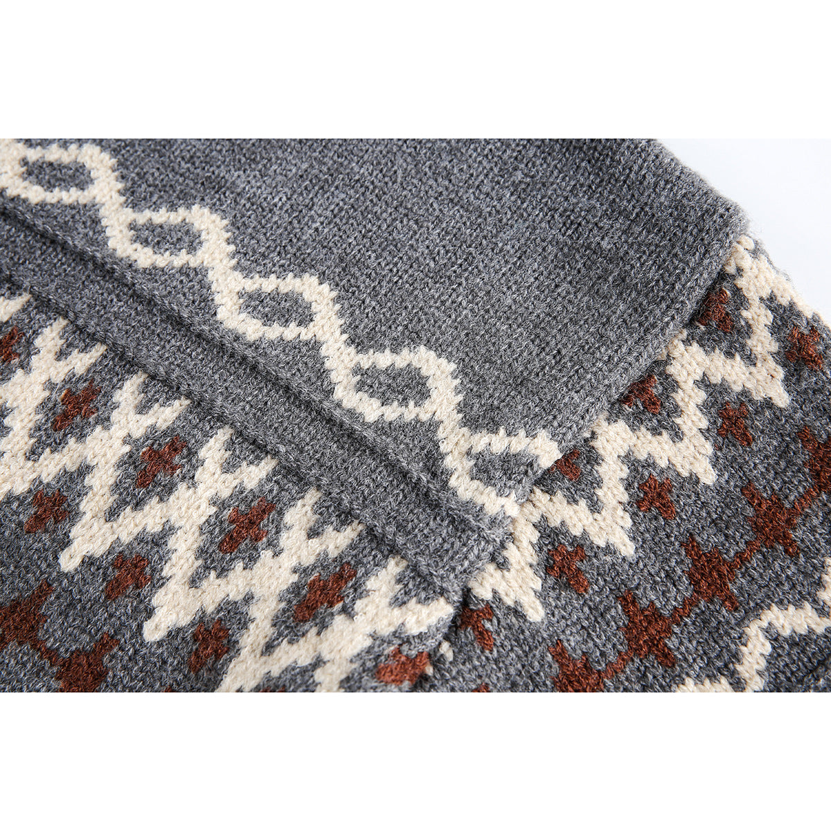 Close-up of charcoal sweater knit with cream and rust geometric bands and a folded seam.