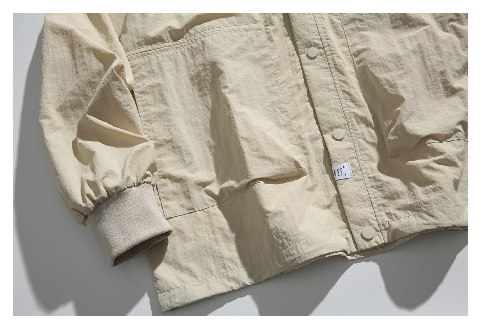 Close-up of the beige jacket’s patch pocket, snap-front placket, and wide ribbed cuff.