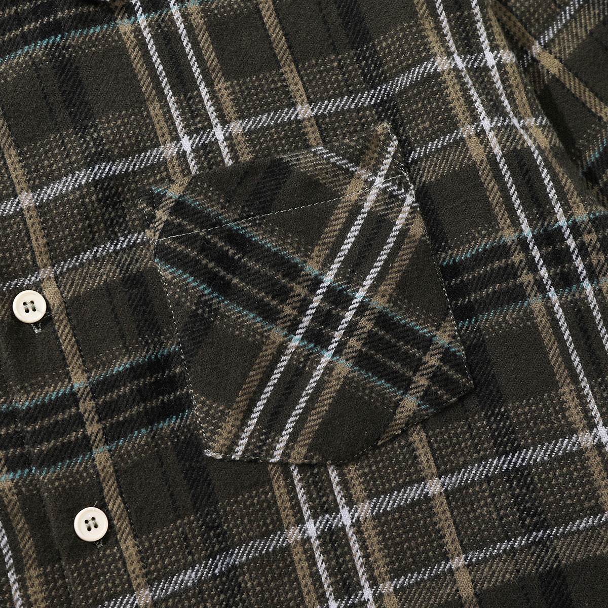 Close-up of a chest pocket and cream buttons on a dark plaid shirt with tan, white, and teal lines.