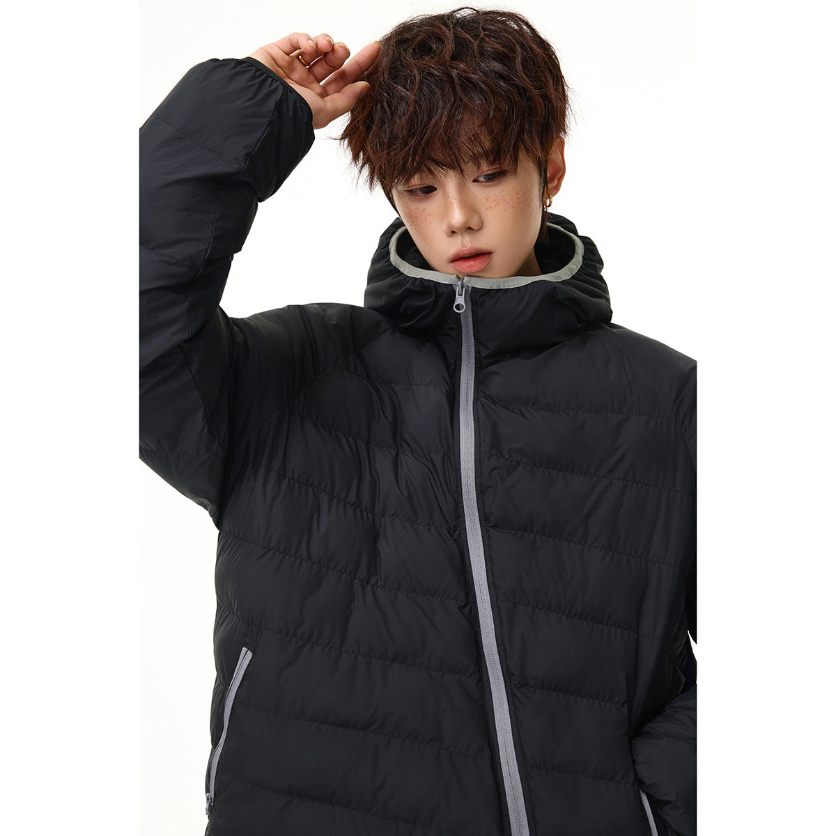 Model wearing a black quilted hooded jacket with a light gray-trimmed hood and zipper.