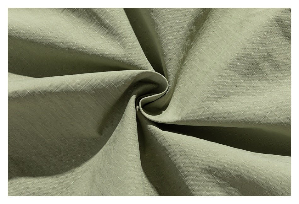 Close-up of olive green fabric gathered into folds, showing a fine crosshatched weave.