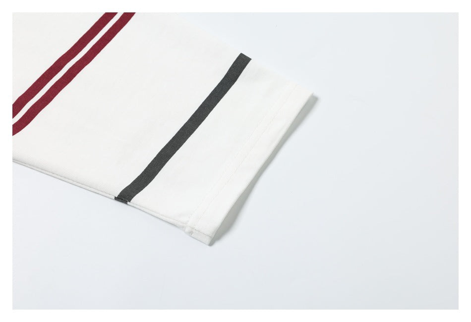 Close-up of a white garment cuff with a black stripe and burgundy double stripes.