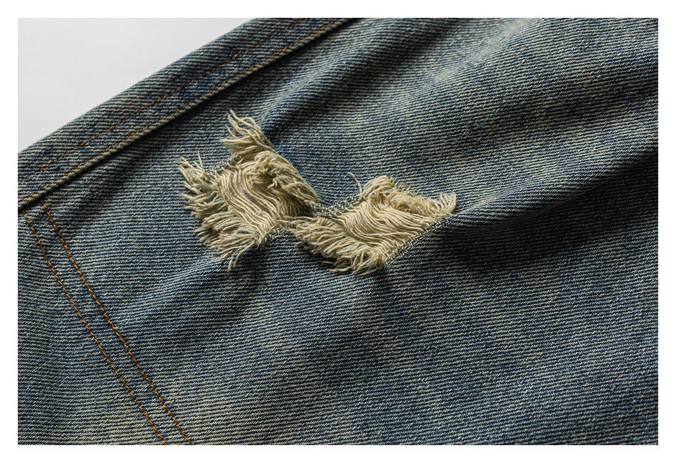 Close-up of a frayed distressed tear on the leg of blue denim shorts.