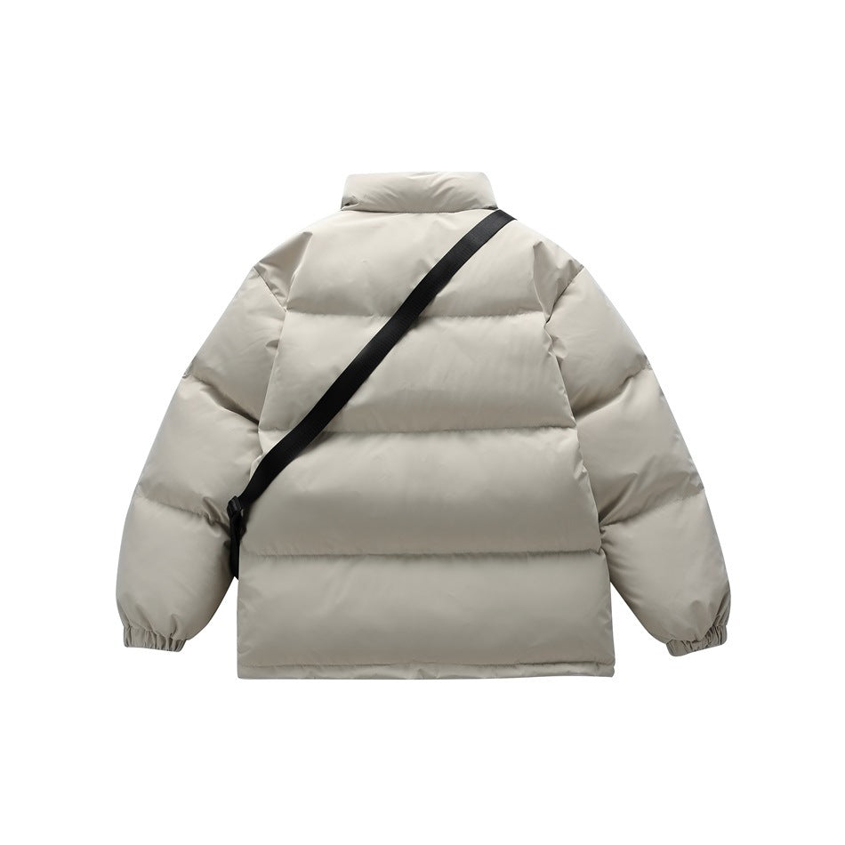 Back view of a light beige quilted puffer jacket with a diagonal black crossbody strap.