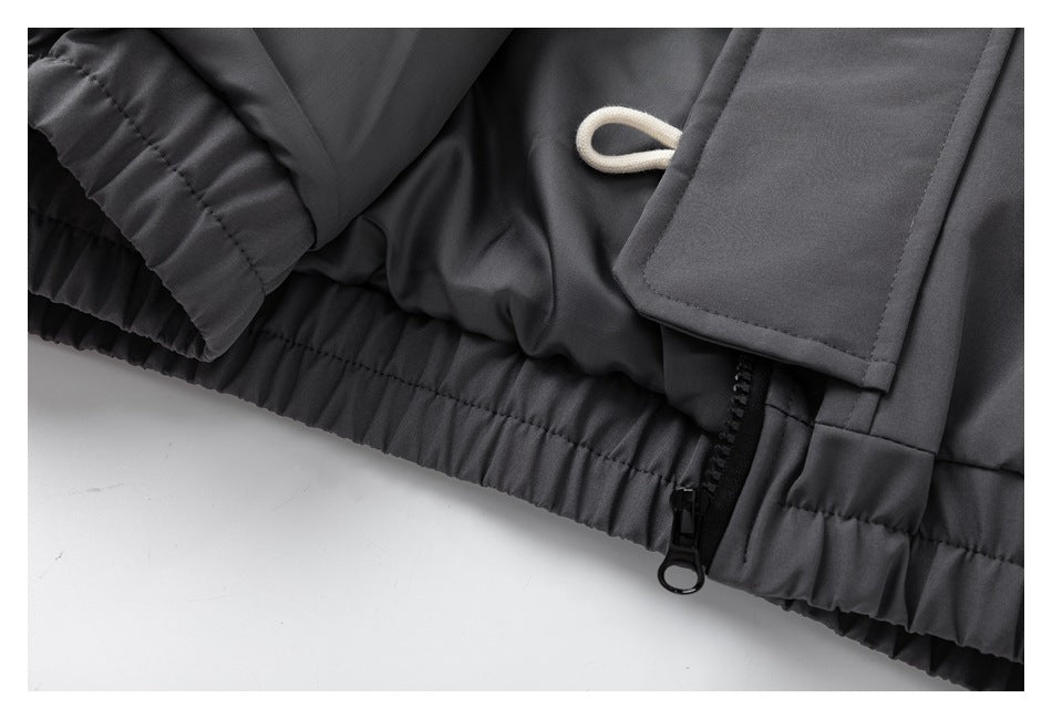 Close-up of the jacket's elasticized hem, zipper, and flap on dark gray fabric.