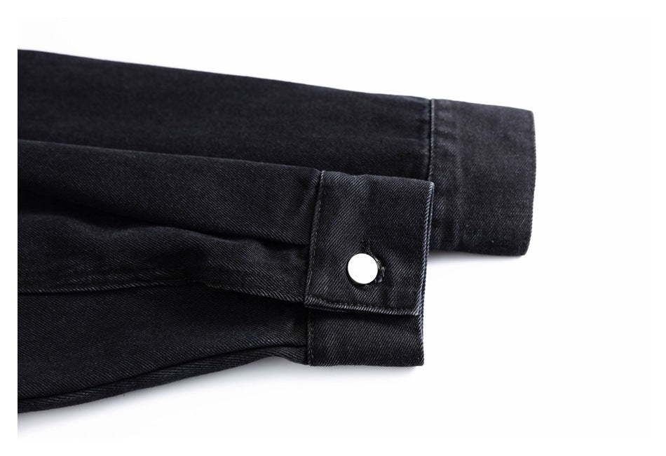 Close-up of a black garment cuff with a silver snap button and stitched tab.