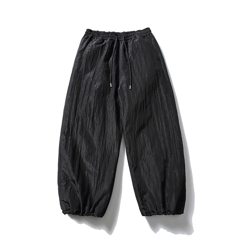 Black wide-leg drawstring pants with crinkled texture and gathered hems, flat front view