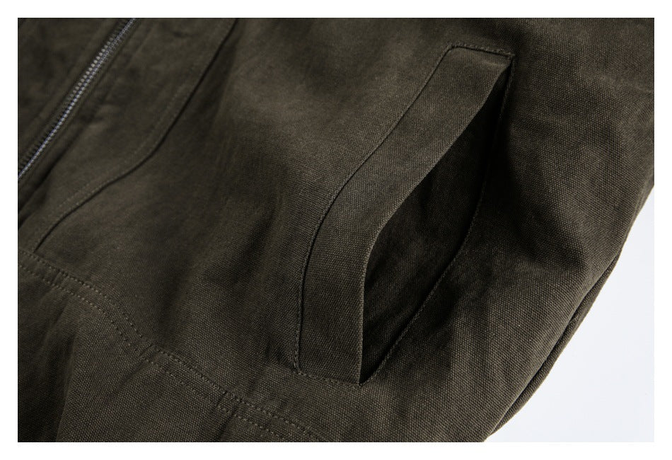 Close-up of an olive-brown jacket's angled side pocket and nearby zipper.