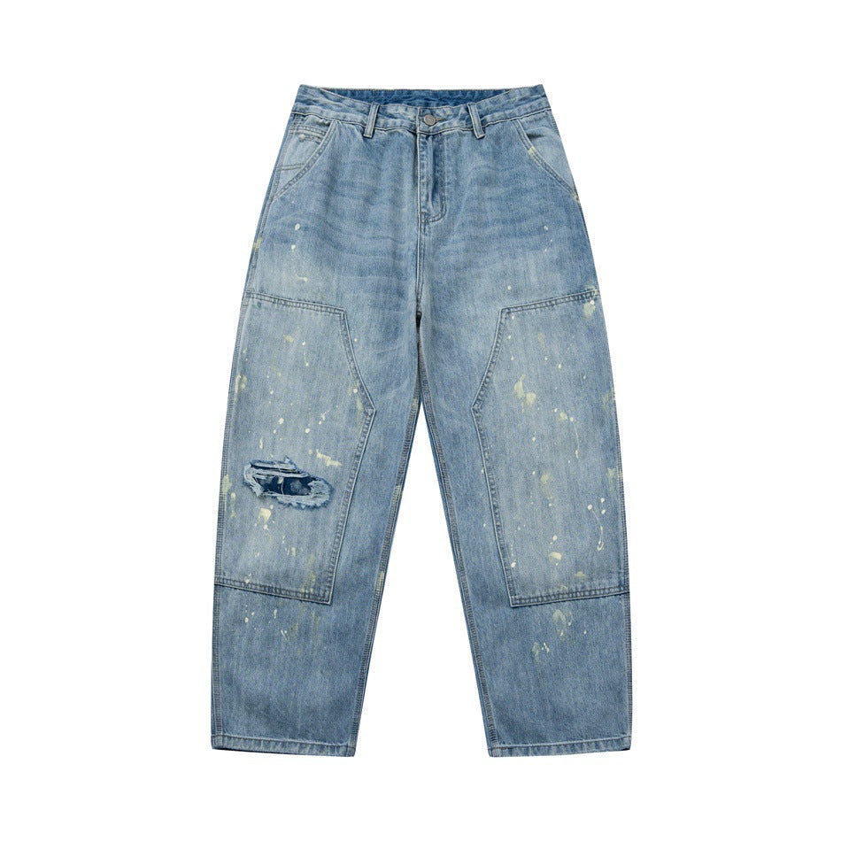 Front of light blue washed jeans with paint splatters, double-knee panels and a frayed knee patch