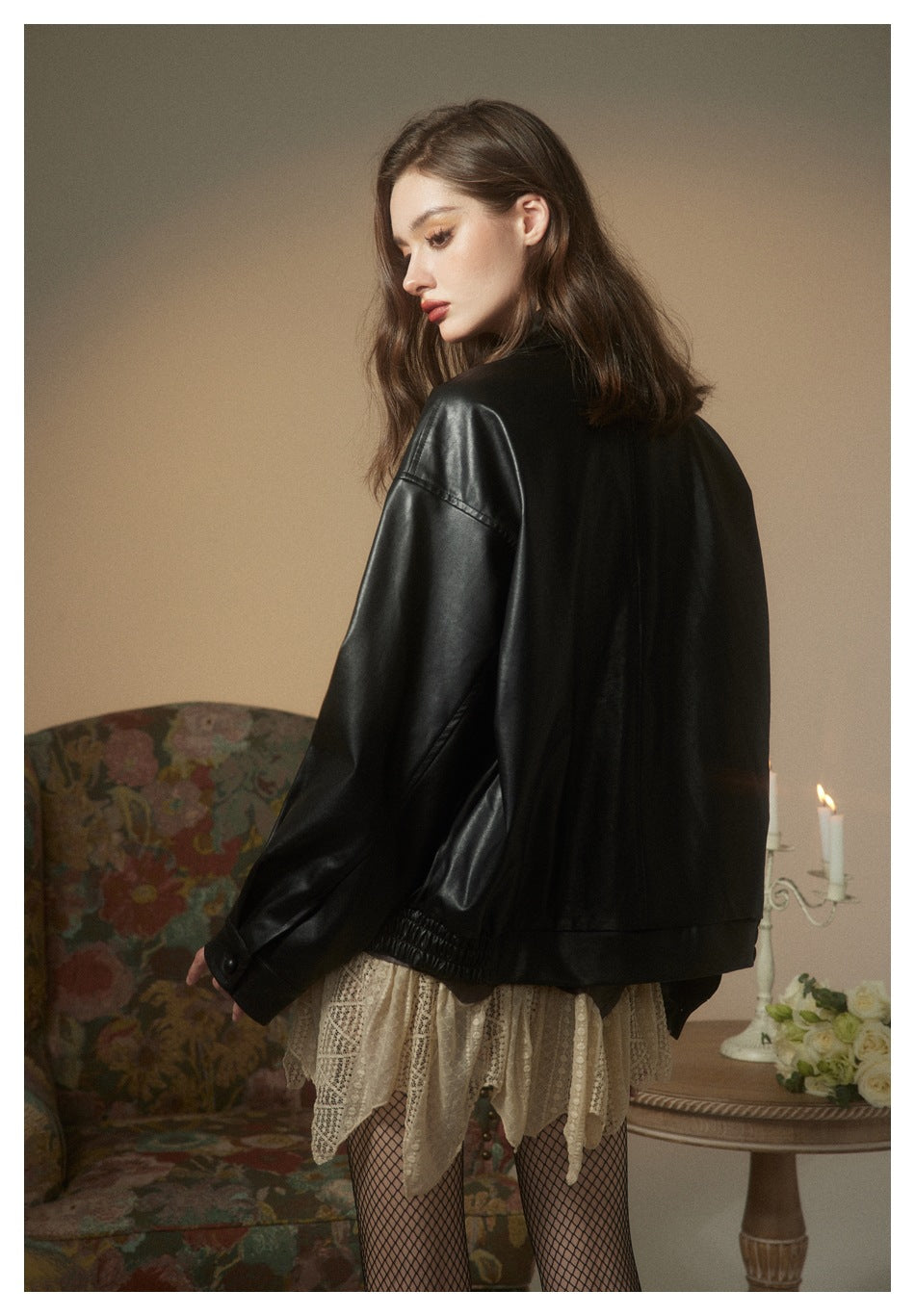 Model looking back while wearing an oversized black jacket with dropped shoulders and a gathered hem.