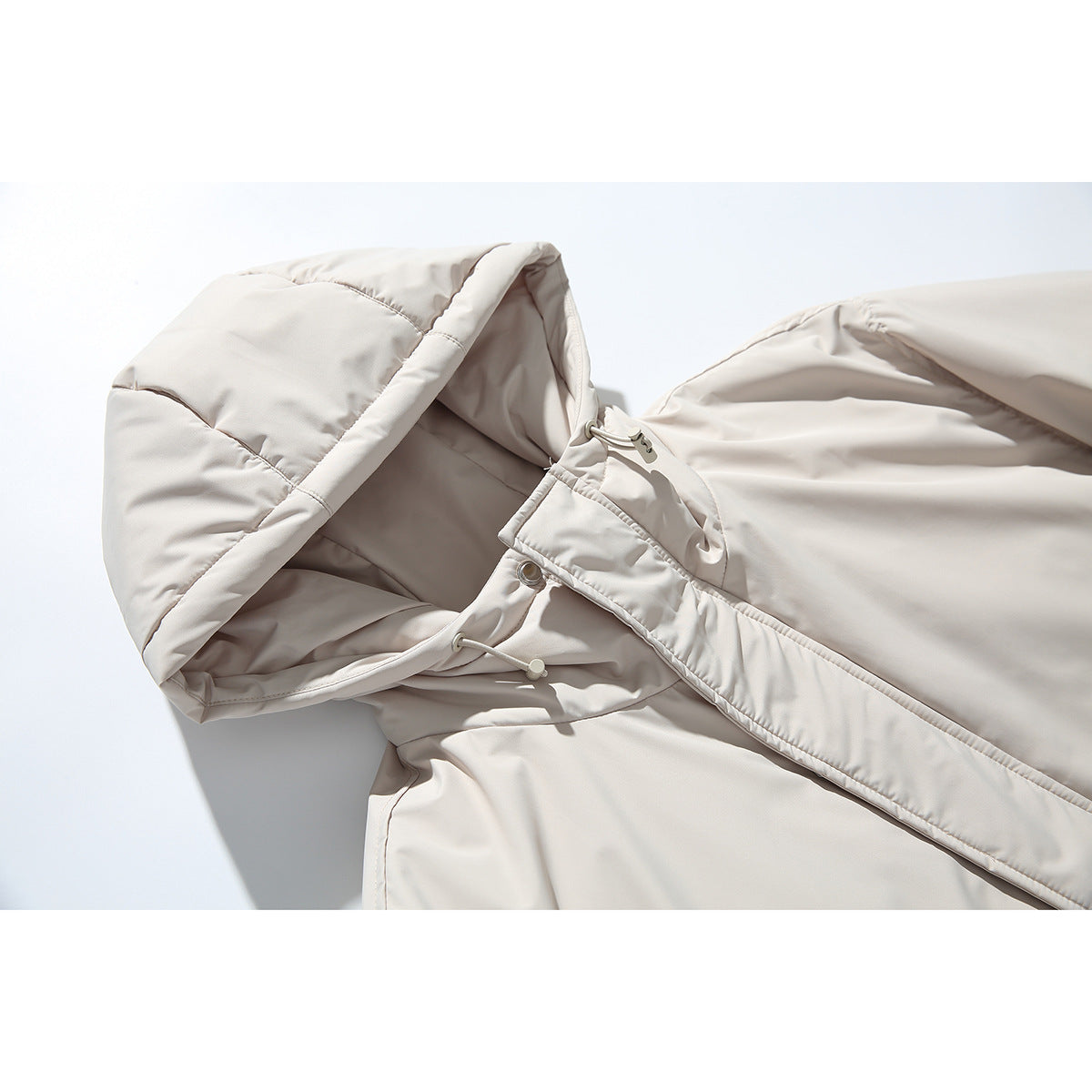 Close-up of a light beige parka hood, drawcords, and front snap placket.
