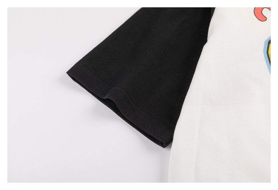 Close-up of a black sleeve beside an off-white shirt body with a small portion of colorful print visible.