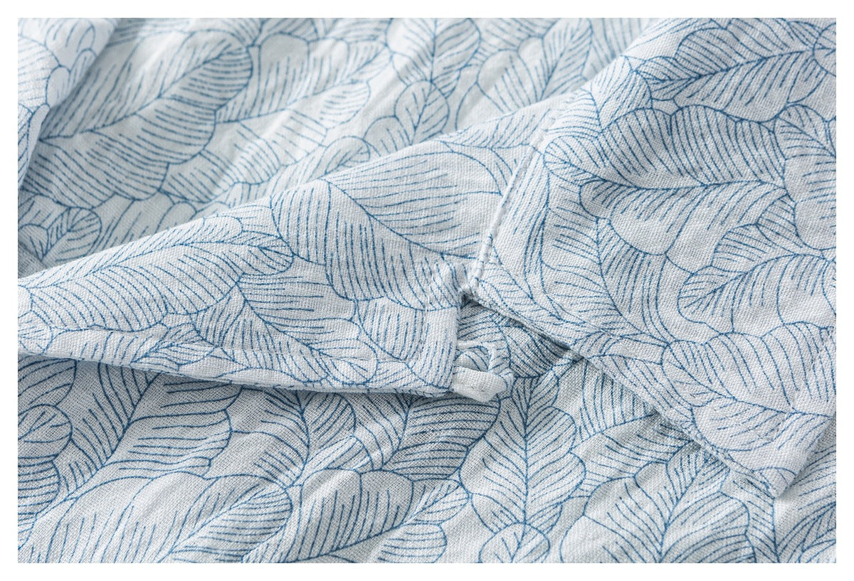 Close-up of a folded shirt sleeve and seam in pale fabric with a blue outlined leaf pattern.