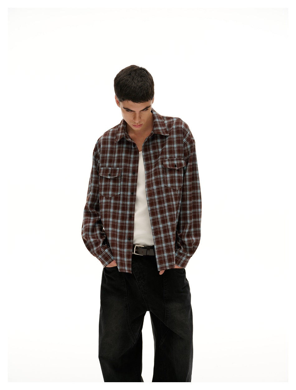 Closer view of a model wearing a brown plaid button-up over a white tank with black trousers.