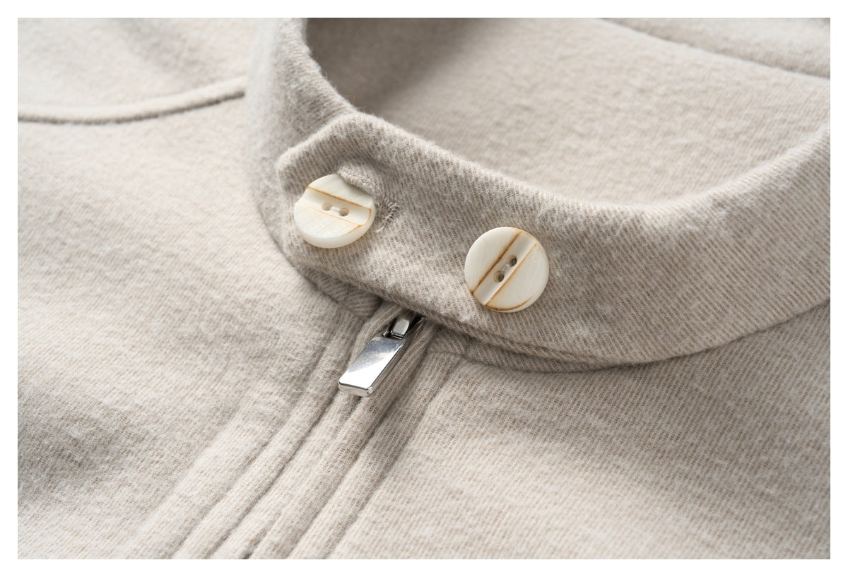 Close-up of a beige heathered garment collar with two cream buttons and a silver zipper pull.