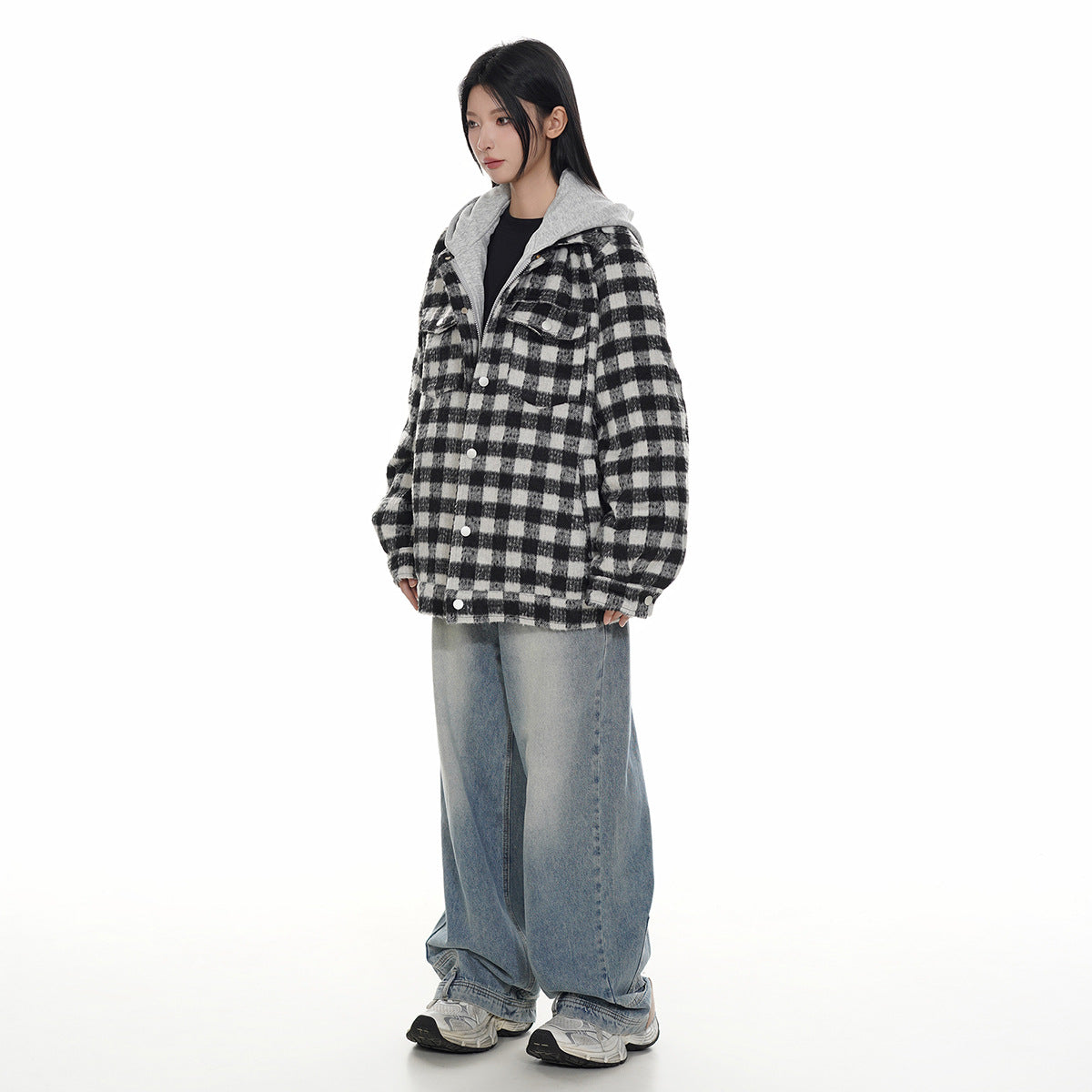 Model wearing a black-and-white plaid hooded jacket with front buttons and loose blue jeans.